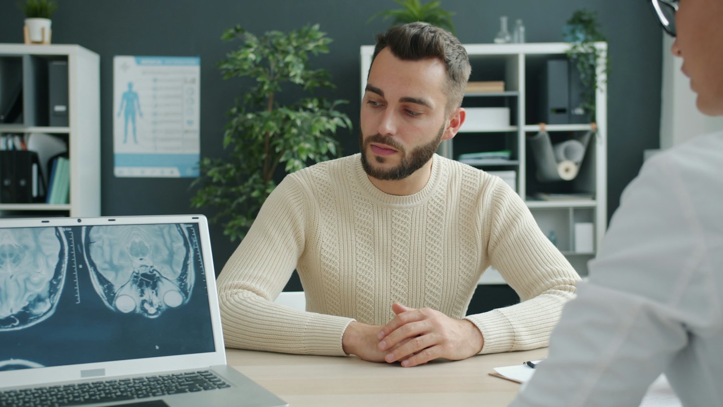 Doctor discusses brain scan results with patient on laptop.