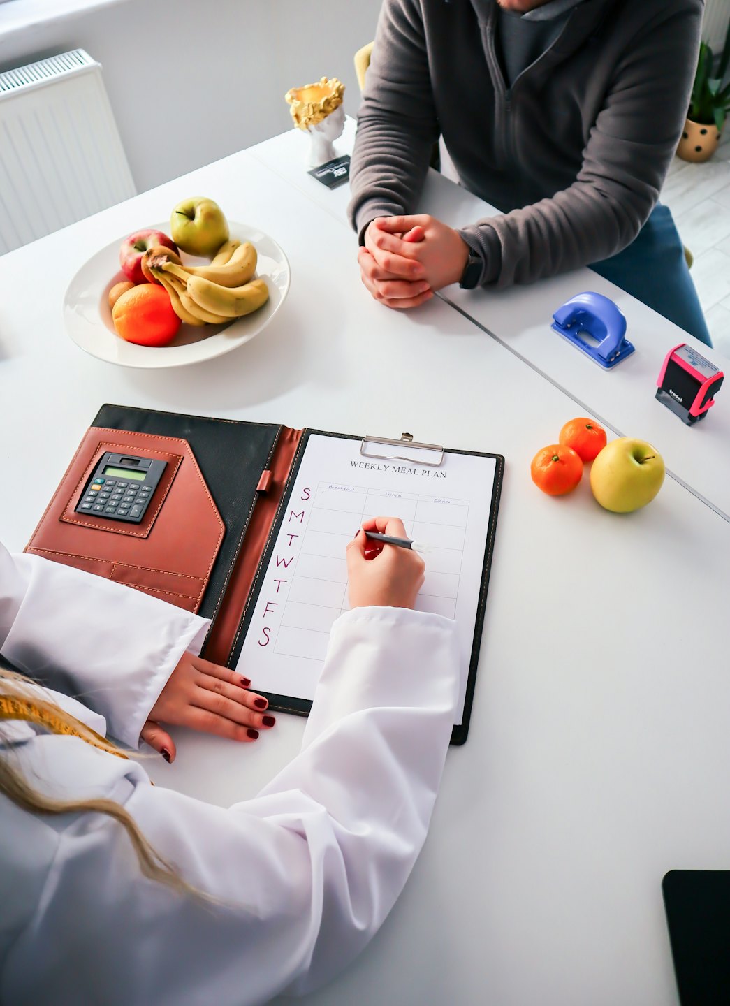 Nutritionist reviewing meal plan with client and fruit.