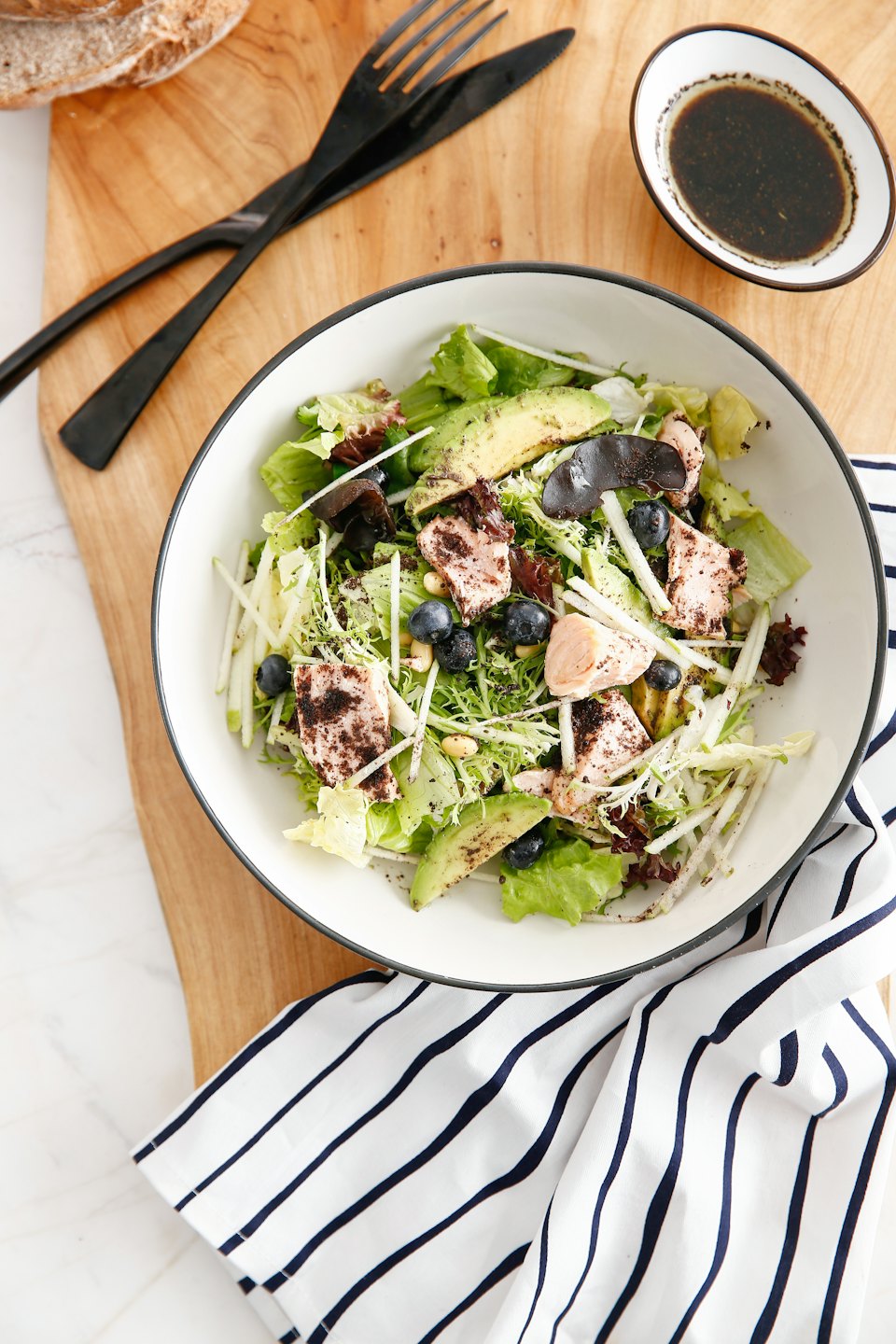 Healthy salad with salmon and avocado on a wooden board.